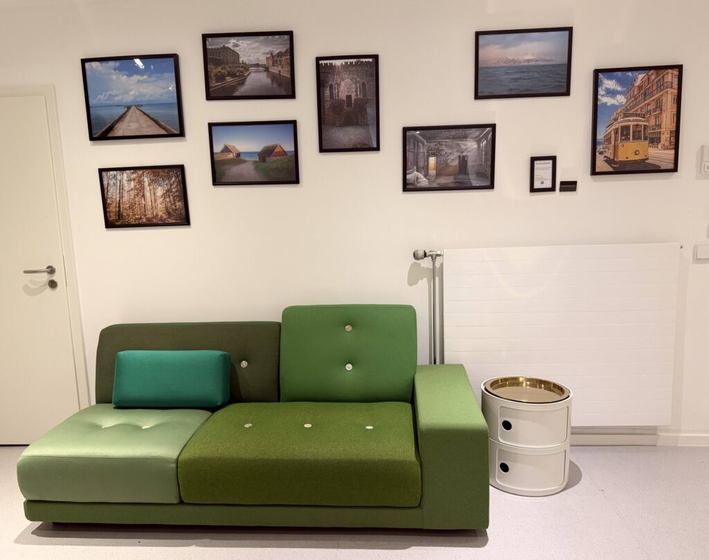 Sitzecke mit grünem Sofa und gerahmten Fotografien an der Wand